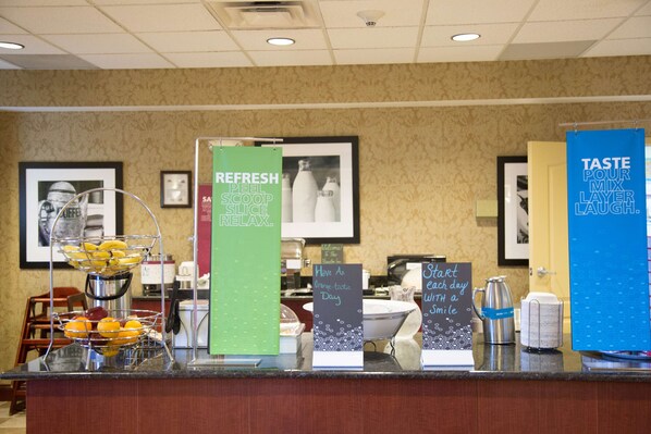 A buffet counter with various food items and signs promoting a fresh peel, scoop, and slice experience. - Hampton Inn Morehead (Morehead)