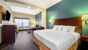 A hotel room with a large bed, a desk, a chair, a TV, and a window with curtains. - La Quinta Inn & Suites by Wyndham Longview North (Longview)