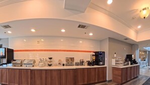 A modern kitchen with a curved island, built-in appliances, and a tiled backsplash. - La Quinta Inn & Suites by Wyndham Longview North (Longview)
