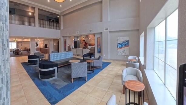A spacious lobby with a high ceiling, a central seating area, and a view of the sky through large windows. - La Quinta Inn & Suites by Wyndham Longview North (Longview)