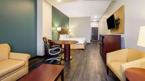 A hotel room with a bed, a desk, two chairs, a TV, and a dresser. - La Quinta Inn & Suites by Wyndham Longview North (Longview)