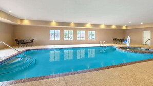 A large indoor swimming pool with clear blue water, surrounded by beige walls and large windows. - La Quinta Inn & Suites by Wyndham Longview North (Longview)