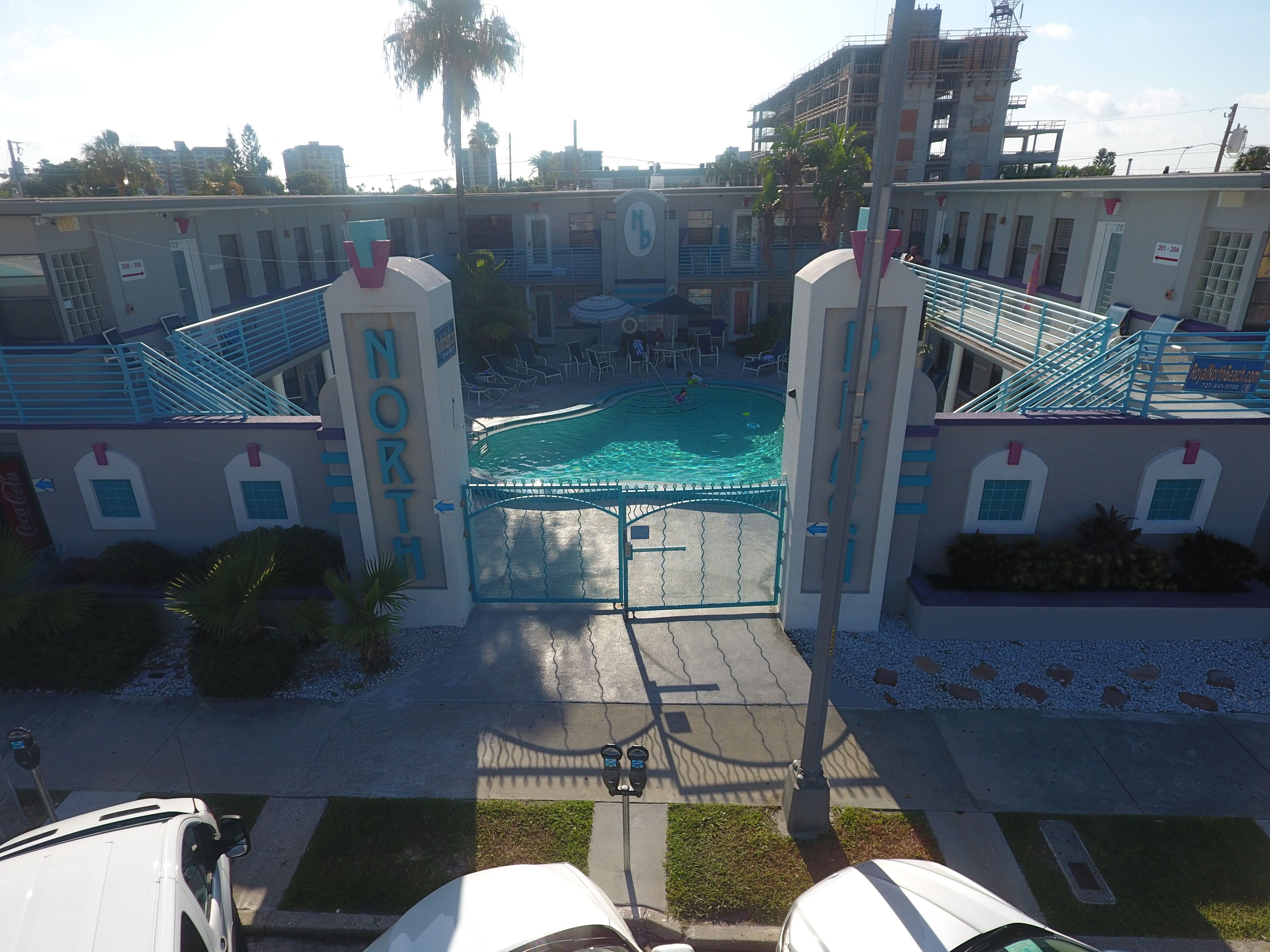 A hotel entrance with a pool, a sign reading "NORTH", and a parking area with cars.