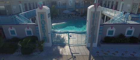A hotel entrance with a pool, a sign reading "NORTH", and a parking area with cars.