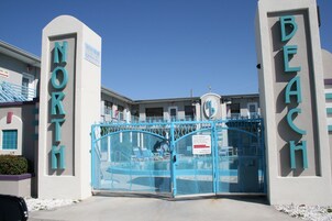 Una entrada cerrada con letreros que indican 'NORTH BEACH', un área de piscina y un edificio con un reloj.