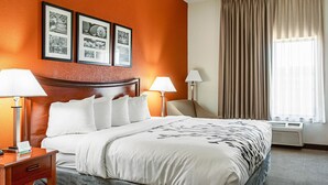 Une chambre d’hôtel avec un grand lit, deux lampes de chevet, une tête de lit et un mur décoré de tableaux encadrés.