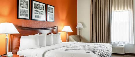 A hotel room with a large bed, two bedside lamps, a headboard, and a wall with framed pictures.