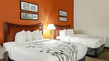 Een hotelkamer met twee bedden, een nachtkastje met een lamp, en lijstjes aan de oranje muur.