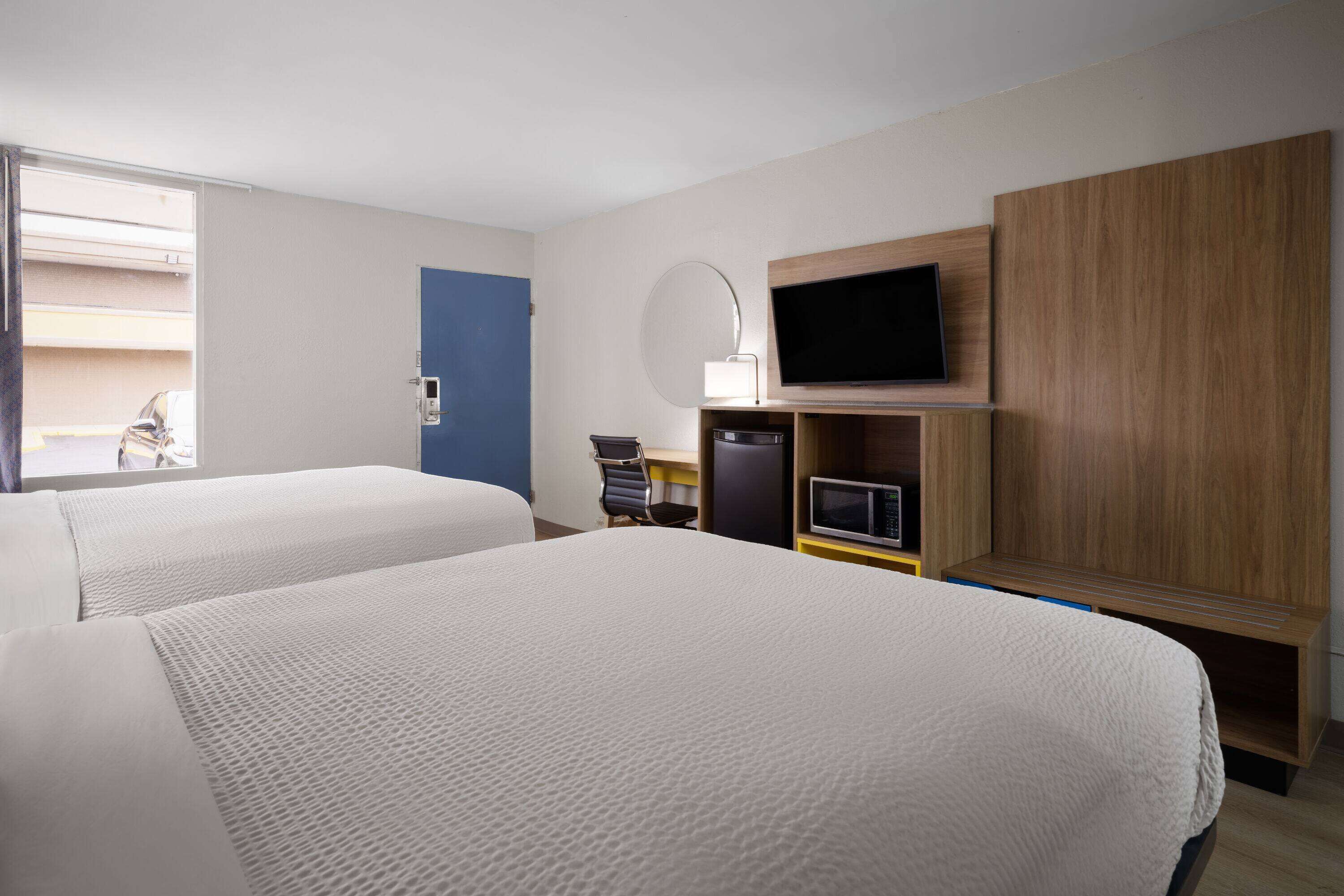 Une chambre d’hôtel avec deux lits, une télévision, un bureau et une chaise.