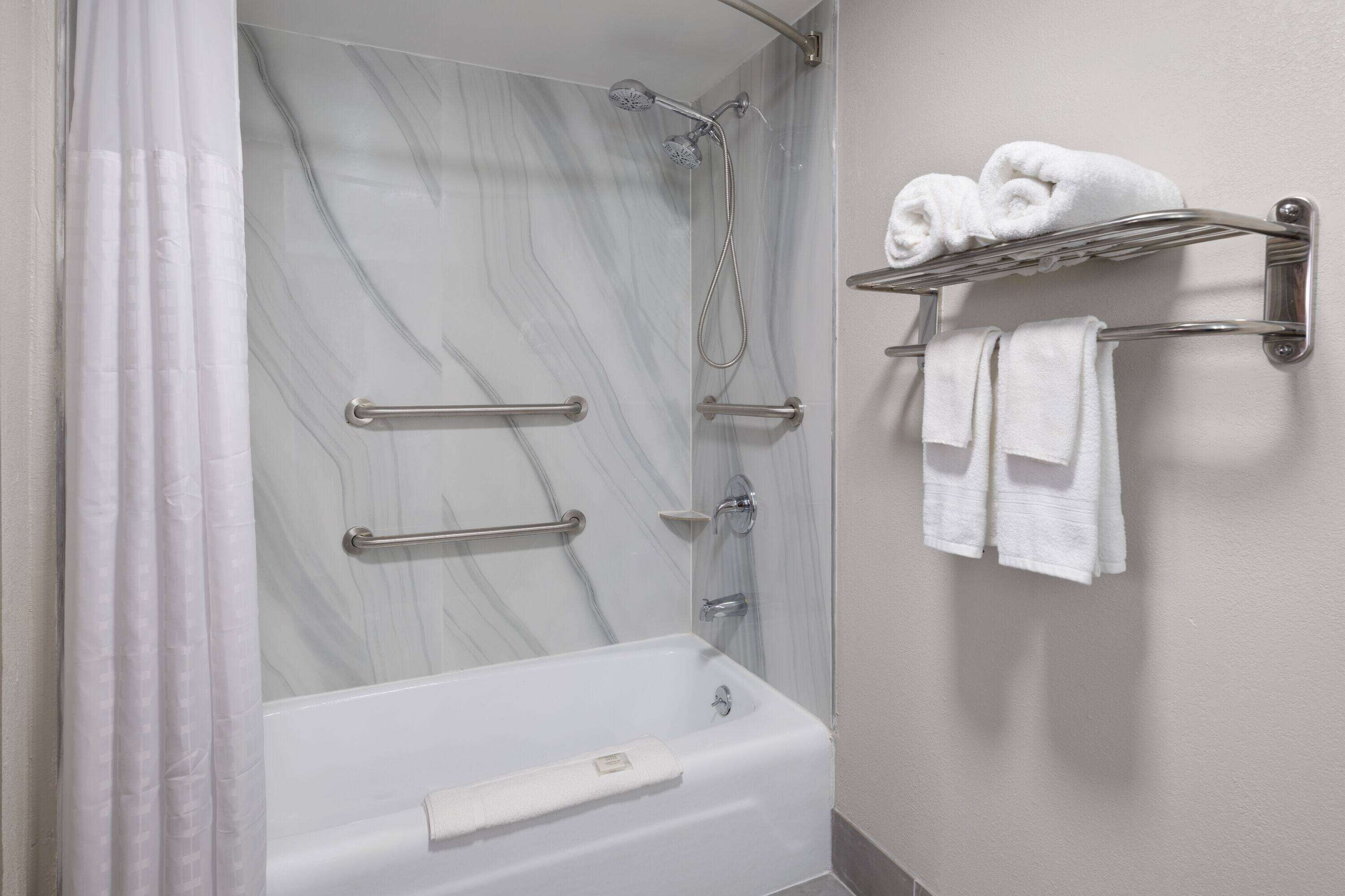 Une salle de bain avec un mur de douche en marbre, une baignoire et un porte-serviettes avec des serviettes.