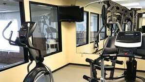 Un gimnasio con equipo cardiovascular, máquinas de pesas y una televisión montada en la pared.