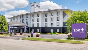 Un hotel de diseño moderno, con un llamativo letrero 'spark by Hilton', un área de entrada bien cuidada y un estacionamiento.
