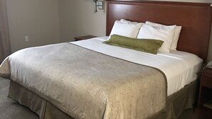 A hotel room with a large bed, a nightstand, a lamp, and a carpeted floor. - Candlewood Suites La Porte by IHG (La Porte)