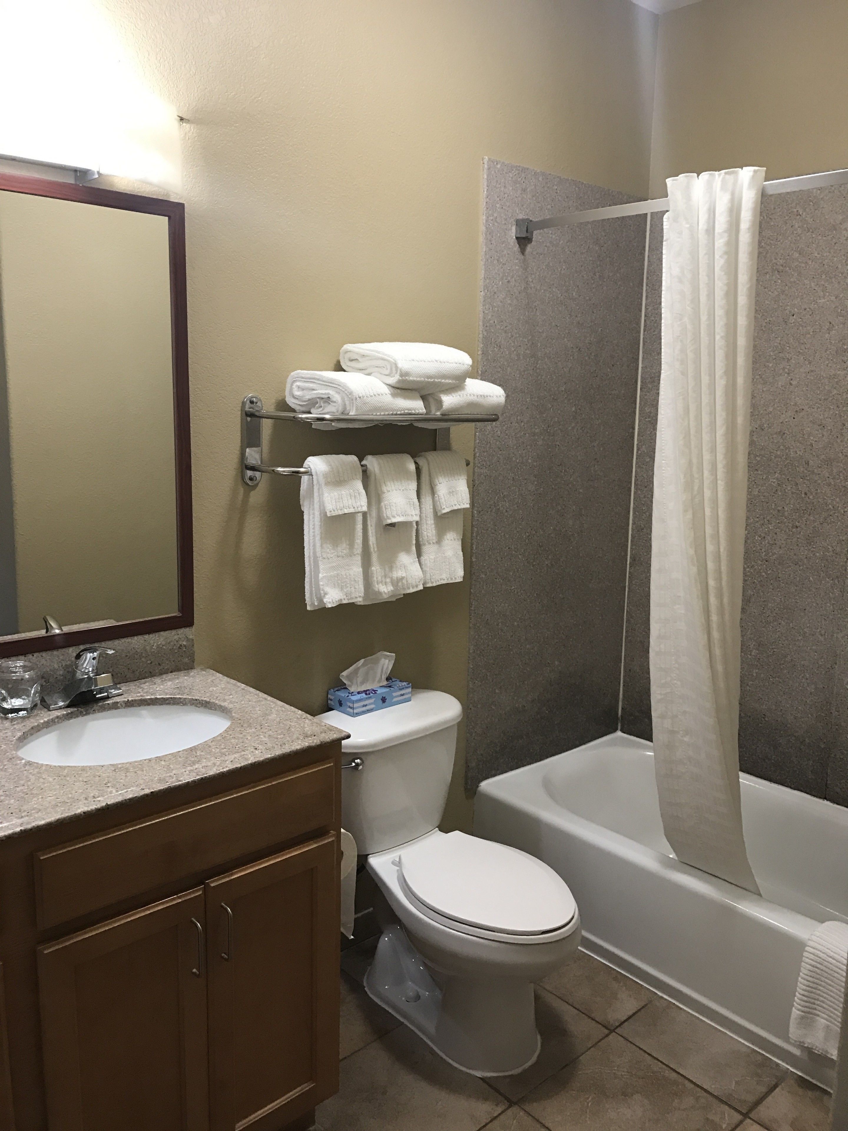 A bathroom with a sink, toilet, and bathtub. There are towels on a rack and a shower curtain.