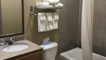 A bathroom with a sink, toilet, and bathtub. There are towels on a rack and a shower curtain.