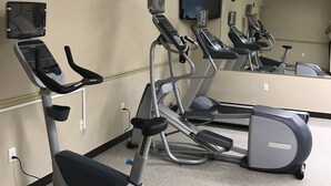 A fitness room with exercise equipment, a clock, and a television. - Candlewood Suites La Porte by IHG (La Porte)