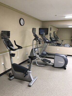 A fitness room with exercise equipment, a clock, and a television. - Candlewood Suites La Porte by IHG (La Porte)