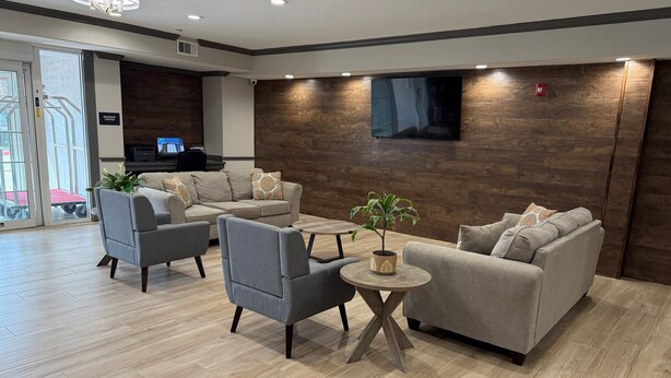 A modern living room with grey sofas, a coffee table, and a potted plant. - Candlewood Suites La Porte by IHG (La Porte)