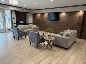 A modern living room with grey sofas, a coffee table, and a potted plant.