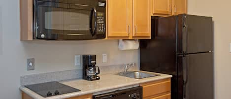 A kitchen with wooden cabinets, a stainless steel refrigerator, a microwave, a dishwasher, and a coffee maker.