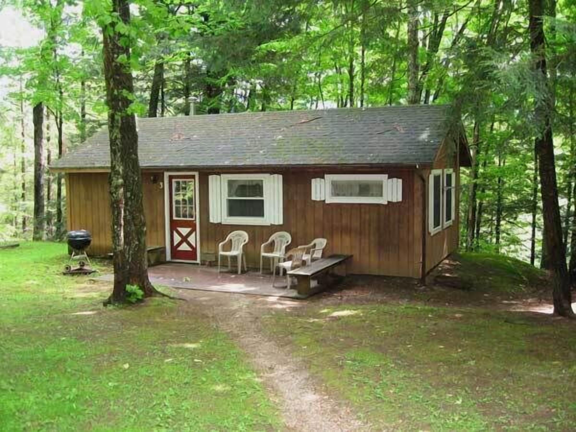 A small wooden cabin with a porch, a door, and two windows.