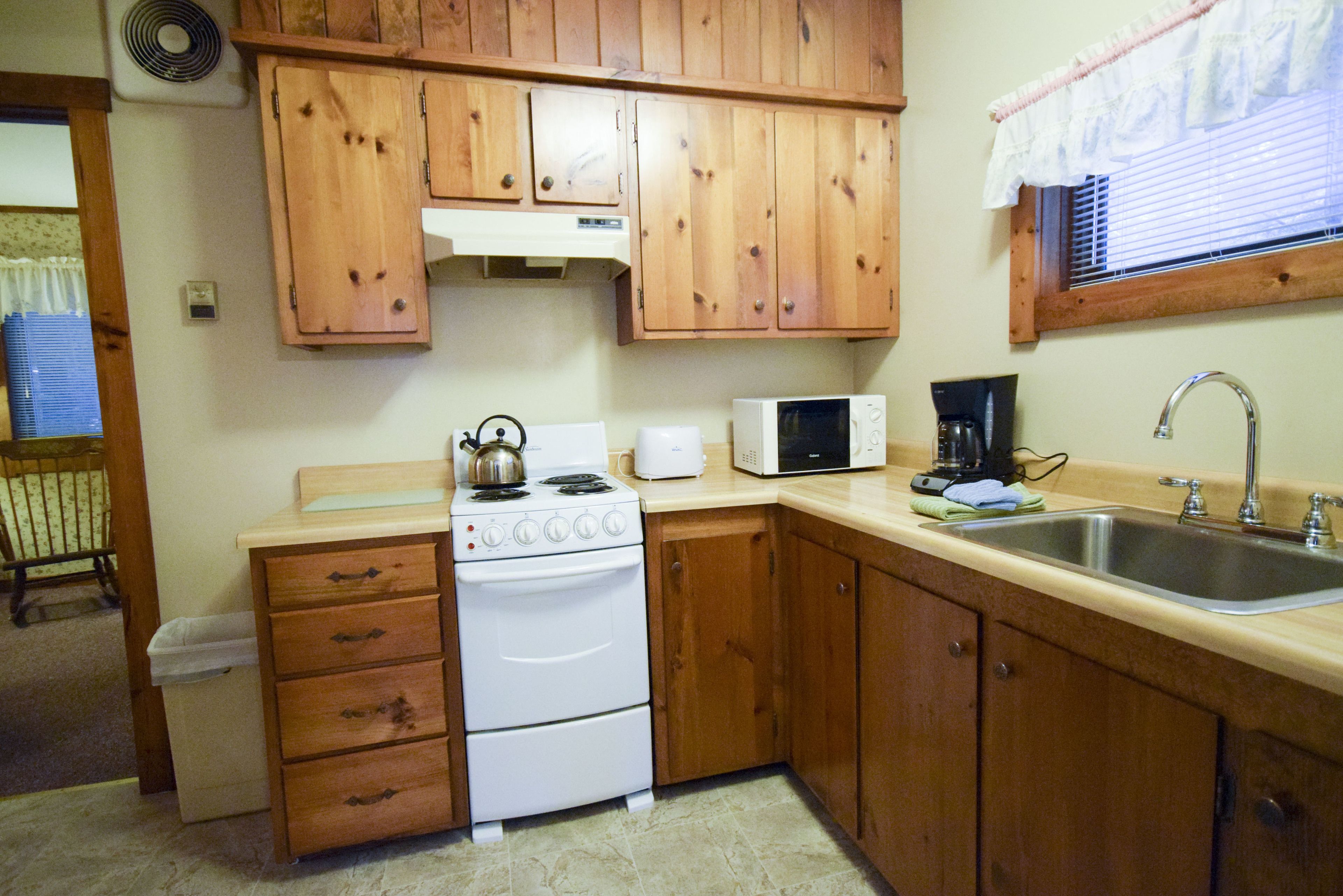 Una cucina con mobili in legno, un fornello bianco, un forno a microonde e un lavello.