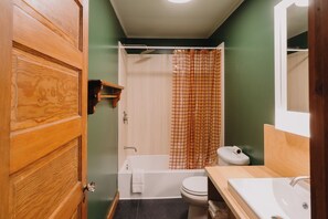 A bathroom with a wooden door, a bathtub, a toilet, and a sink.