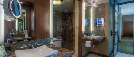 Un baño moderno con un espejo grande, dos lavamanos y una zona de ducha.