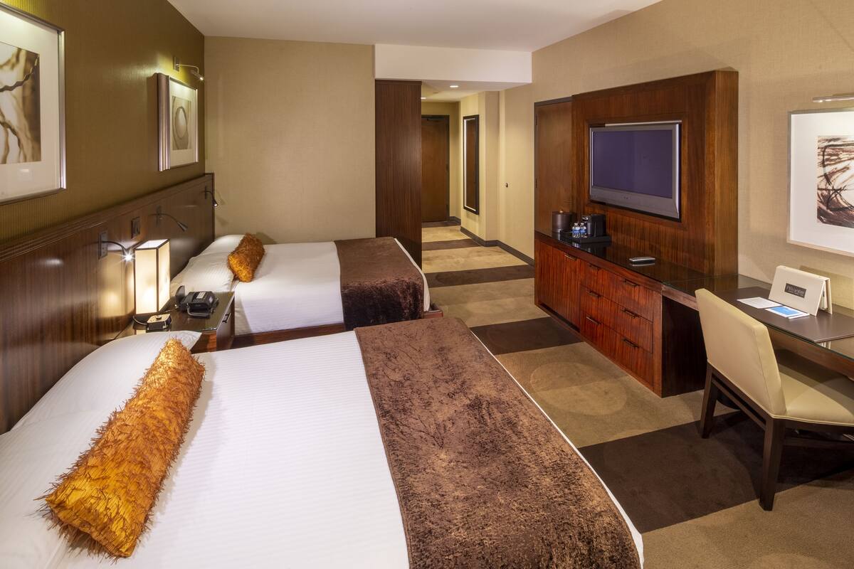 Een hotelkamer met twee bedden, een bureau, een televisie en een minibars.