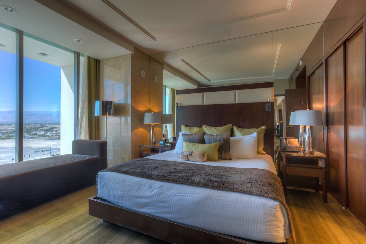 Een moderne hotelkamer met een groot bed, een zithoek en uitzicht op de stad.