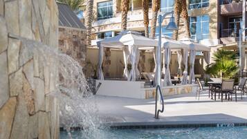 Relax by the resort pool surrounded by a waterfall feature and lounge chairs.