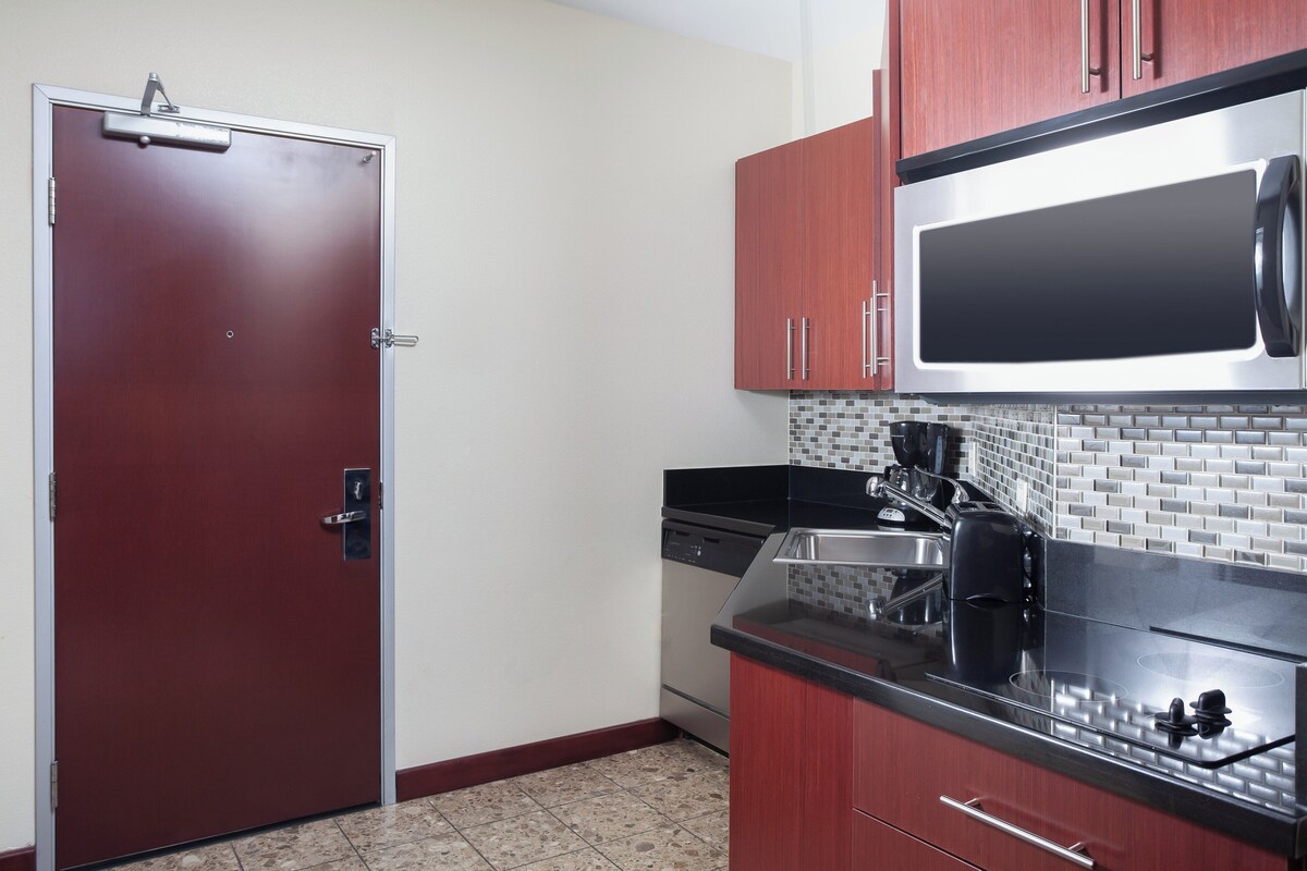 A compact kitchen with a microwave, dishwasher, and a tiled backsplash.