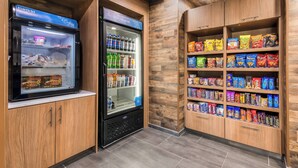 En automattankstation med snacks och drycker, och ett kylskåp med varor i en inredning av trä.