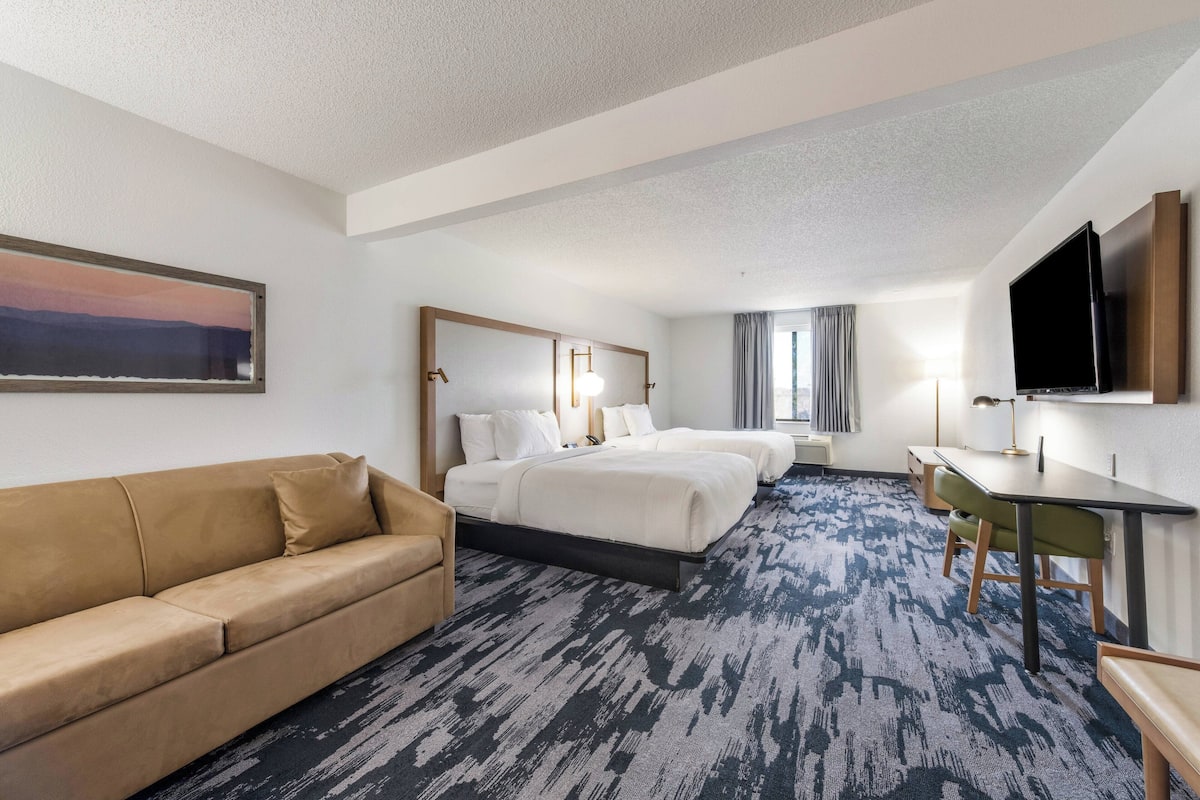 A hotel room with a bed, a sofa, a desk, and a TV.