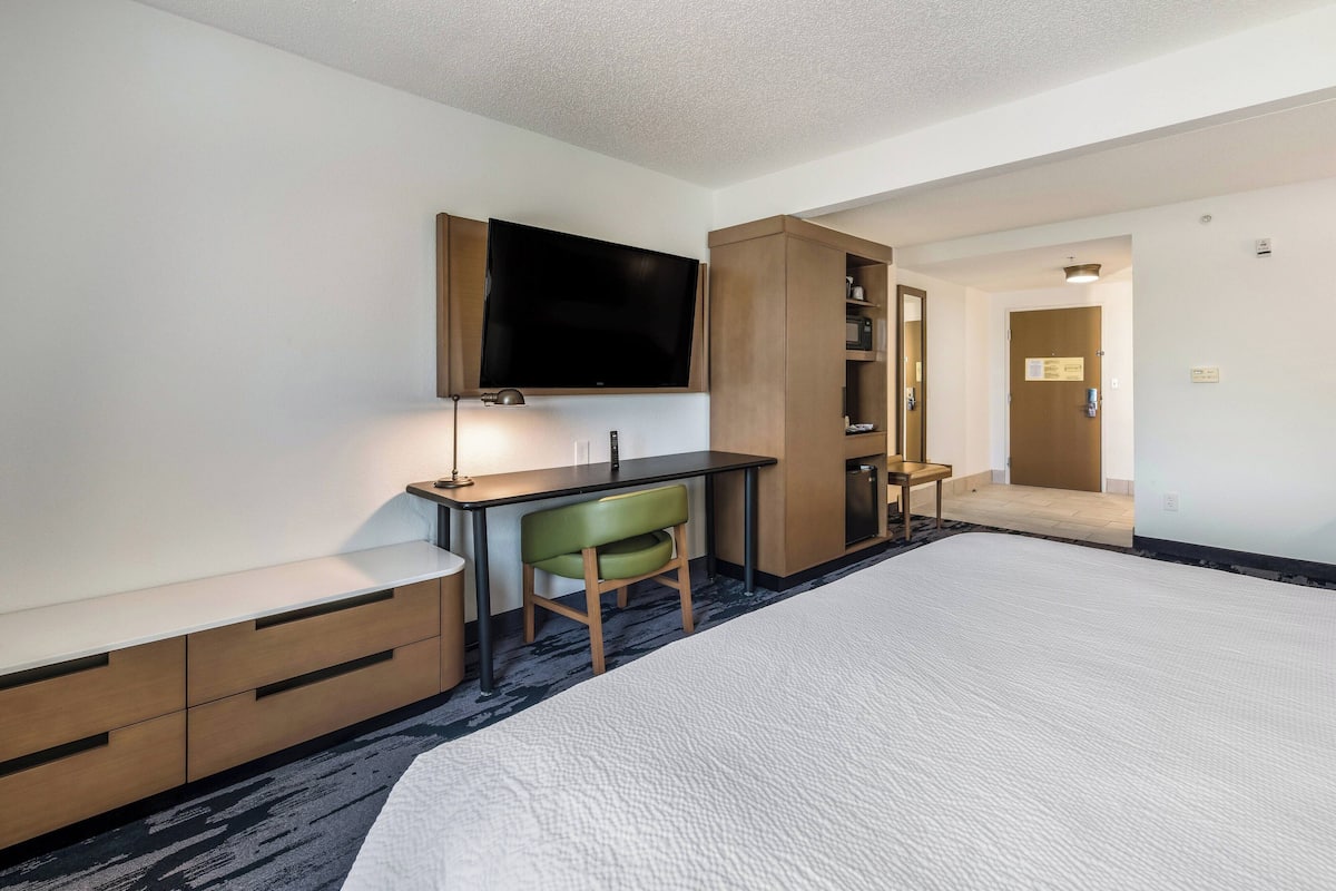 A hotel room with a bed, a desk, a television, and a wardrobe.