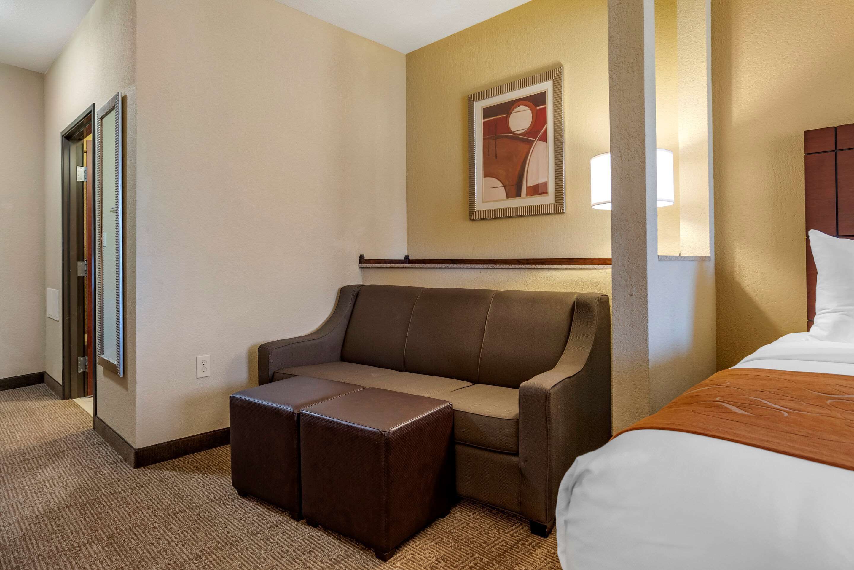 Una habitación de hotel con sofá, reposapiés y cama.