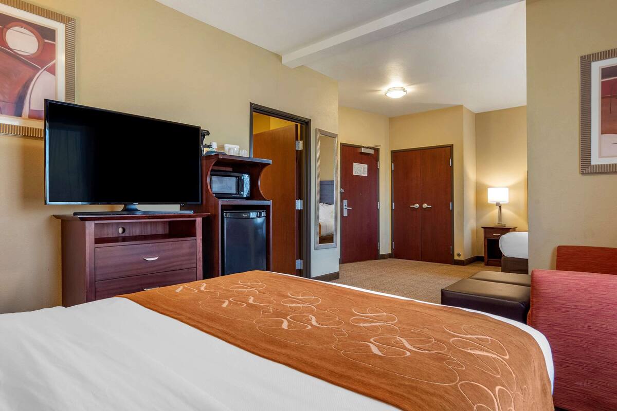 Une chambre d’hôtel équipée d’un lit, d’une télévision, d’un four à micro-ondes, d’un bureau et d’une porte donnant sur une autre pièce.