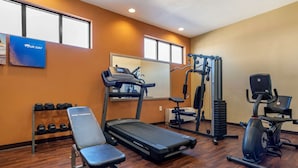 A gym with a treadmill, elliptical, and weight bench.