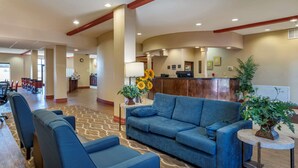 A hotel lobby with a reception desk, a blue sofa, and a coffee station.