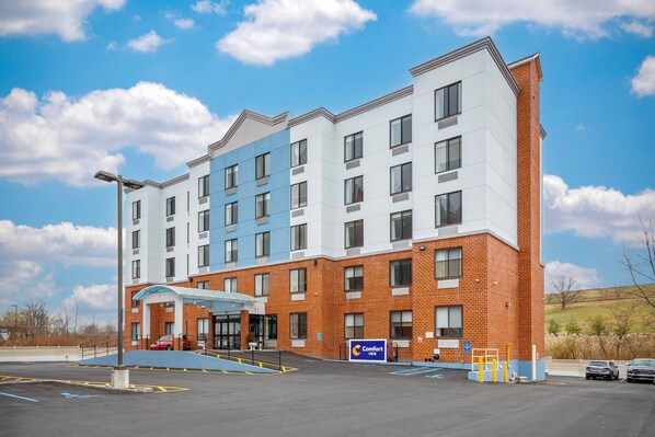 A multi-story hotel with a brick facade and a blue awning over the entrance. - Comfort Inn Staten Island (Staten Island)