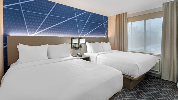 A hotel room with two beds, a large wall mural, a nightstand with a phone, and a window with curtains. - Comfort Inn Staten Island (Staten Island)