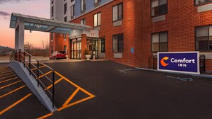 A Comfort Inn hotel entrance with a covered walkway, a parking lot, and a red brick building facade. - Comfort Inn Staten Island (Staten Island)