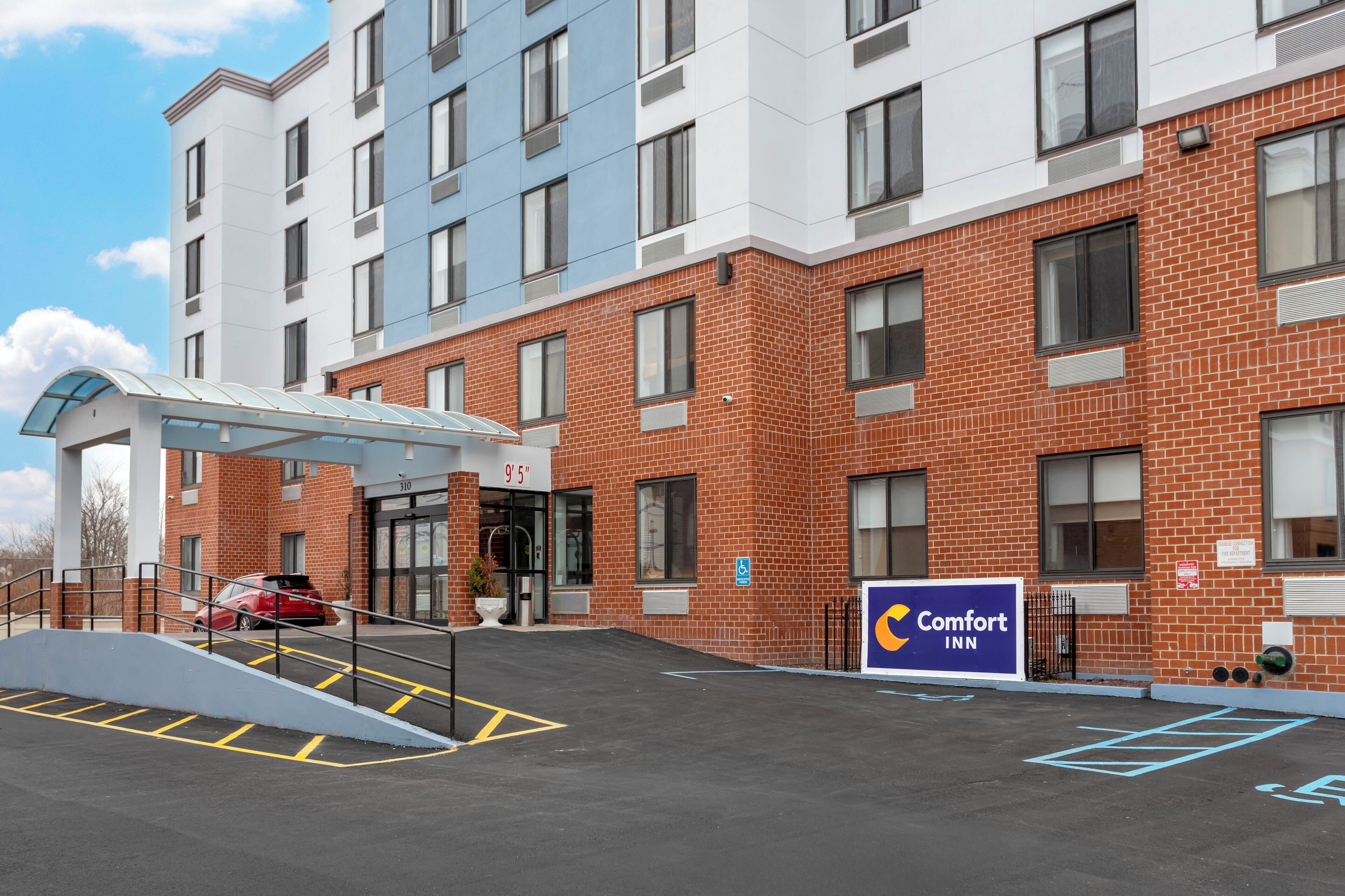 A Comfort Inn hotel with a brick facade, a covered entrance, and a parking area with marked spaces.