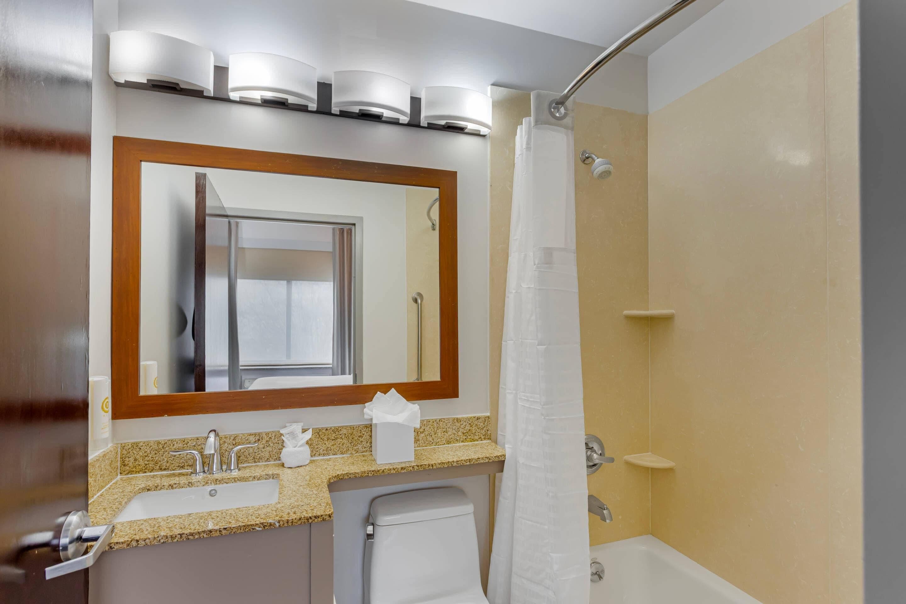 A bathroom with a sink, mirror, and shower.