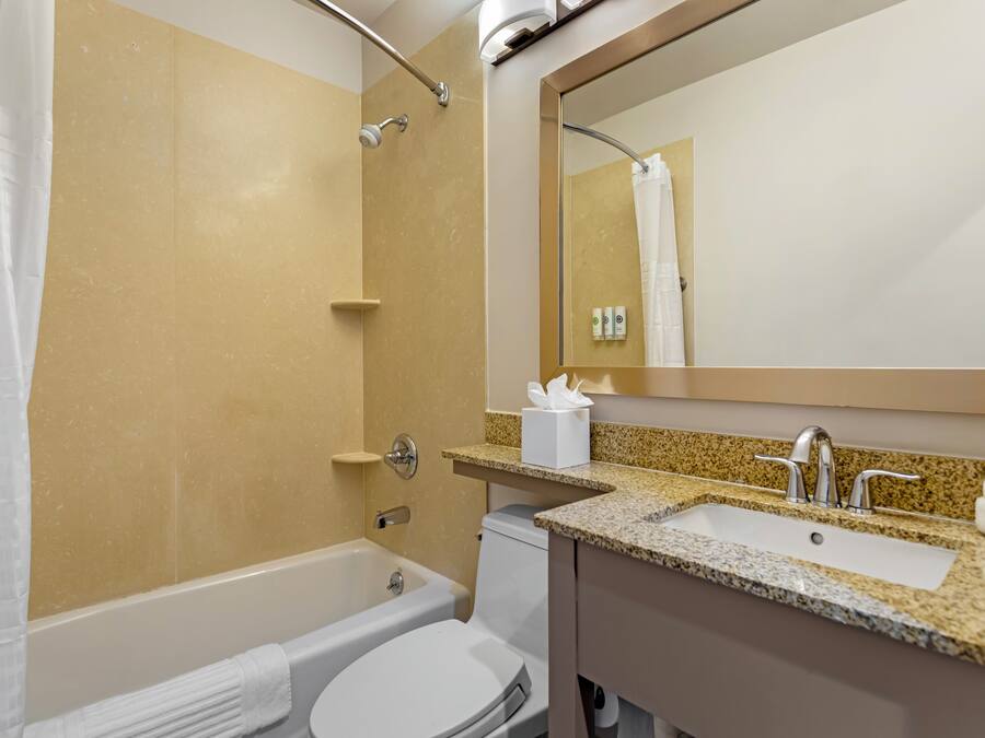 A bathroom with a bathtub, toilet, sink, and a mirror.