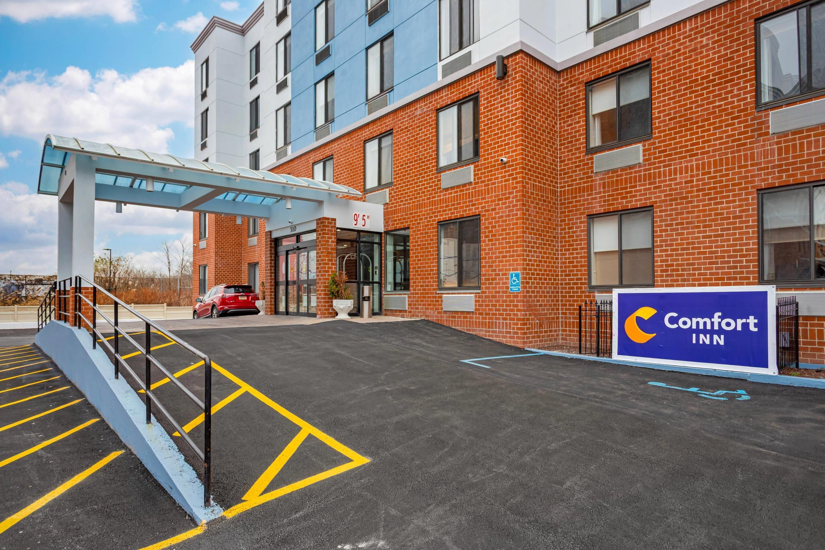Entrada de un hotel Comfort Inn con un corredor cubierto, un estacionamiento y fachada de ladrillo.