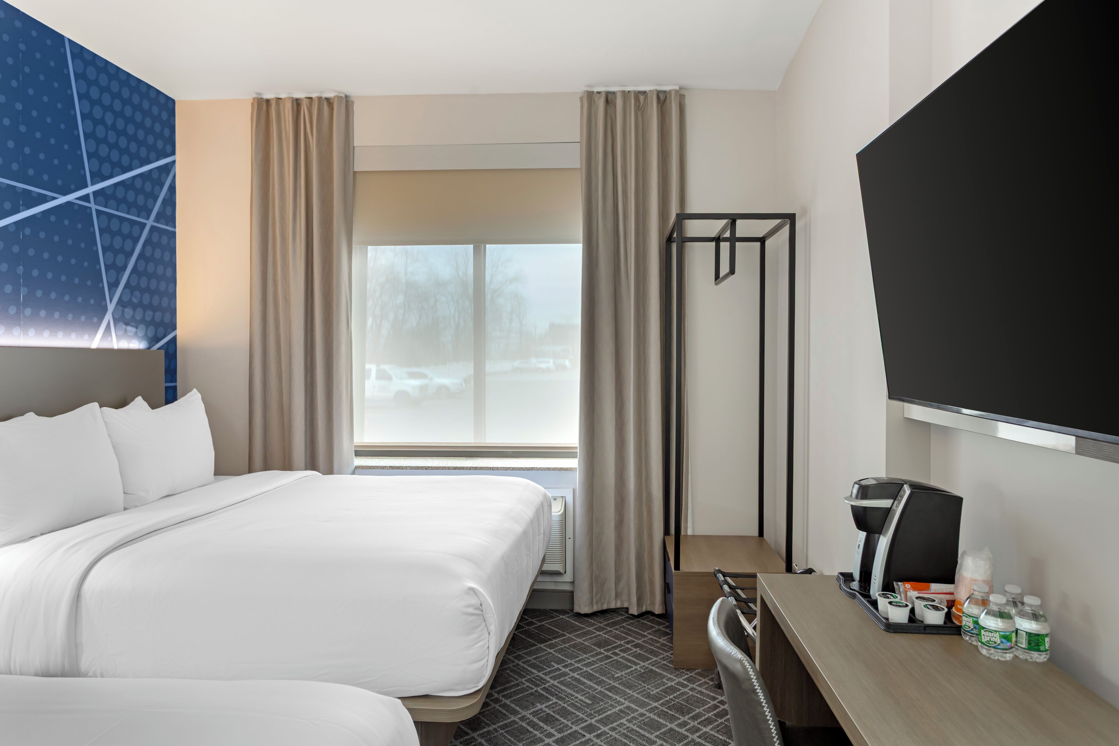 Una habitación de hotel con cama, escritorio con cafetera y televisión.