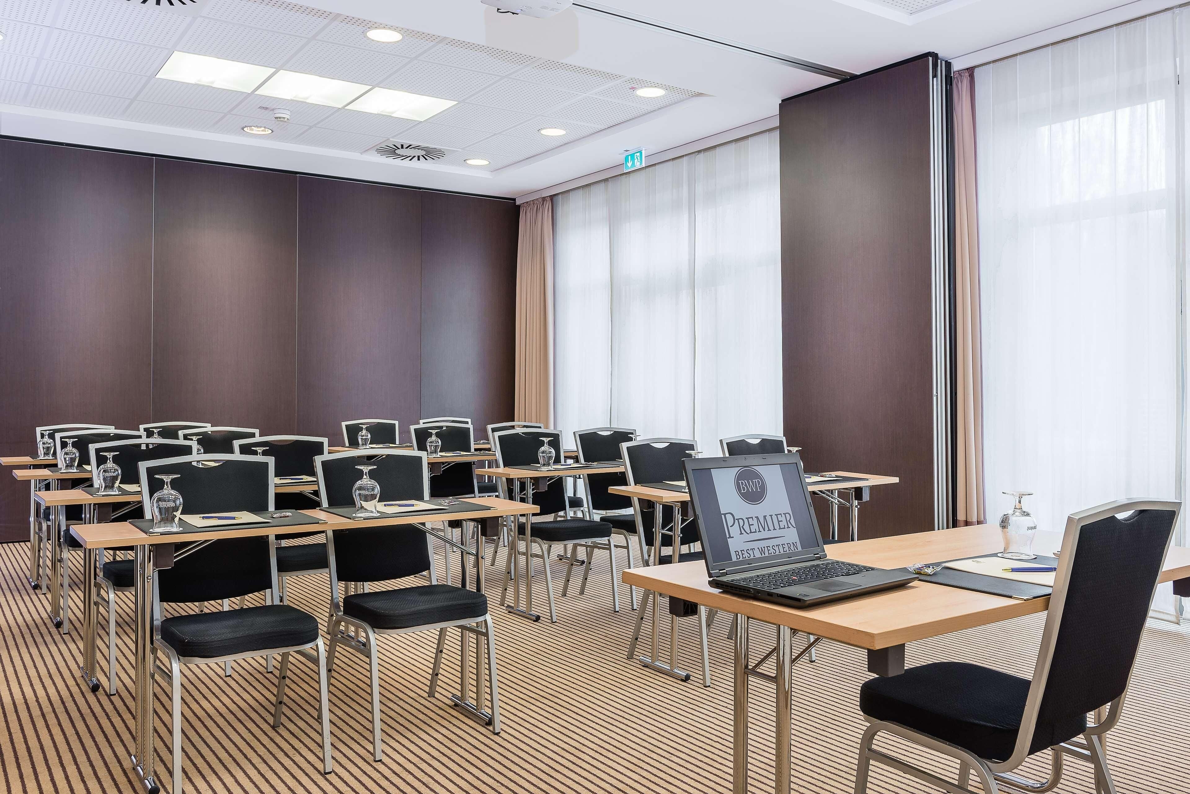 Une salle de conférence dotée de plusieurs tables et chaises, équipée d’ordinateurs portables et de verres.