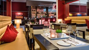 A modern restaurant with leather seating, a bar area with shelves of bottles, and a cityscape view. - Best Western Premier Hotel Regensburg (Regensburg)