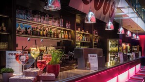 A bar area with shelves of liquor bottles, a counter with a menu, and a seating area with red cushions. - Best Western Premier Hotel Regensburg (Regensburg)